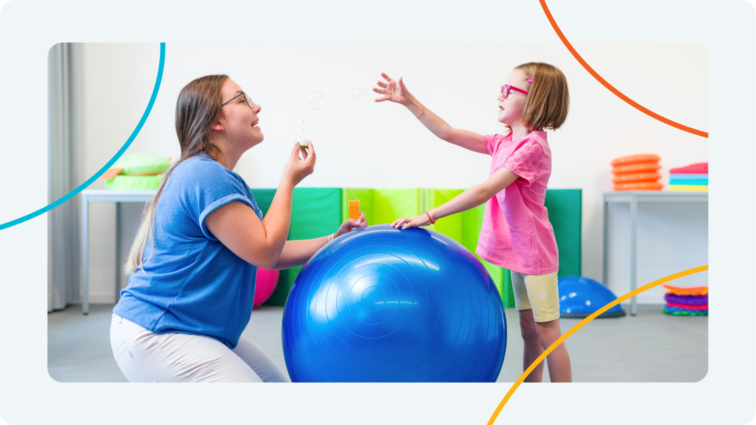 Aya Education pediatric occupational therapy: therapist and child blowing bubbles with blue therapy ball during sensory play